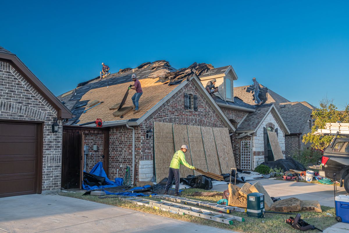 Residential roofing work with exposed underlayment and staged materials